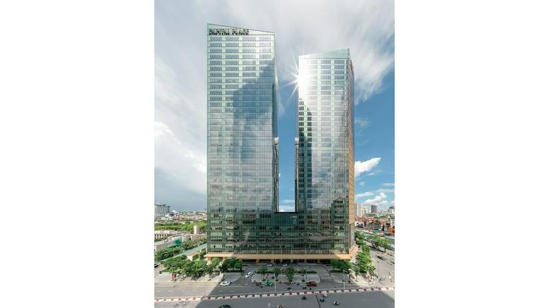 Exterior view of the twin glass towers of the Capital Place Building under a cloudy sky.