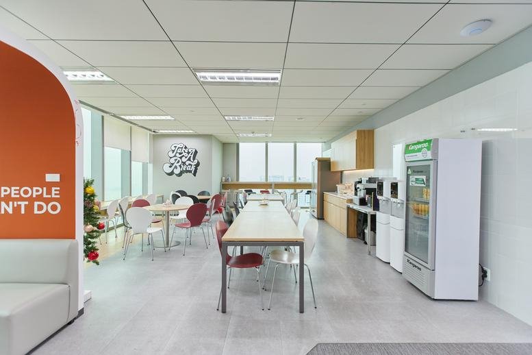 Large breakout area and cafeteria with varied seating, coffee machines, and city views.