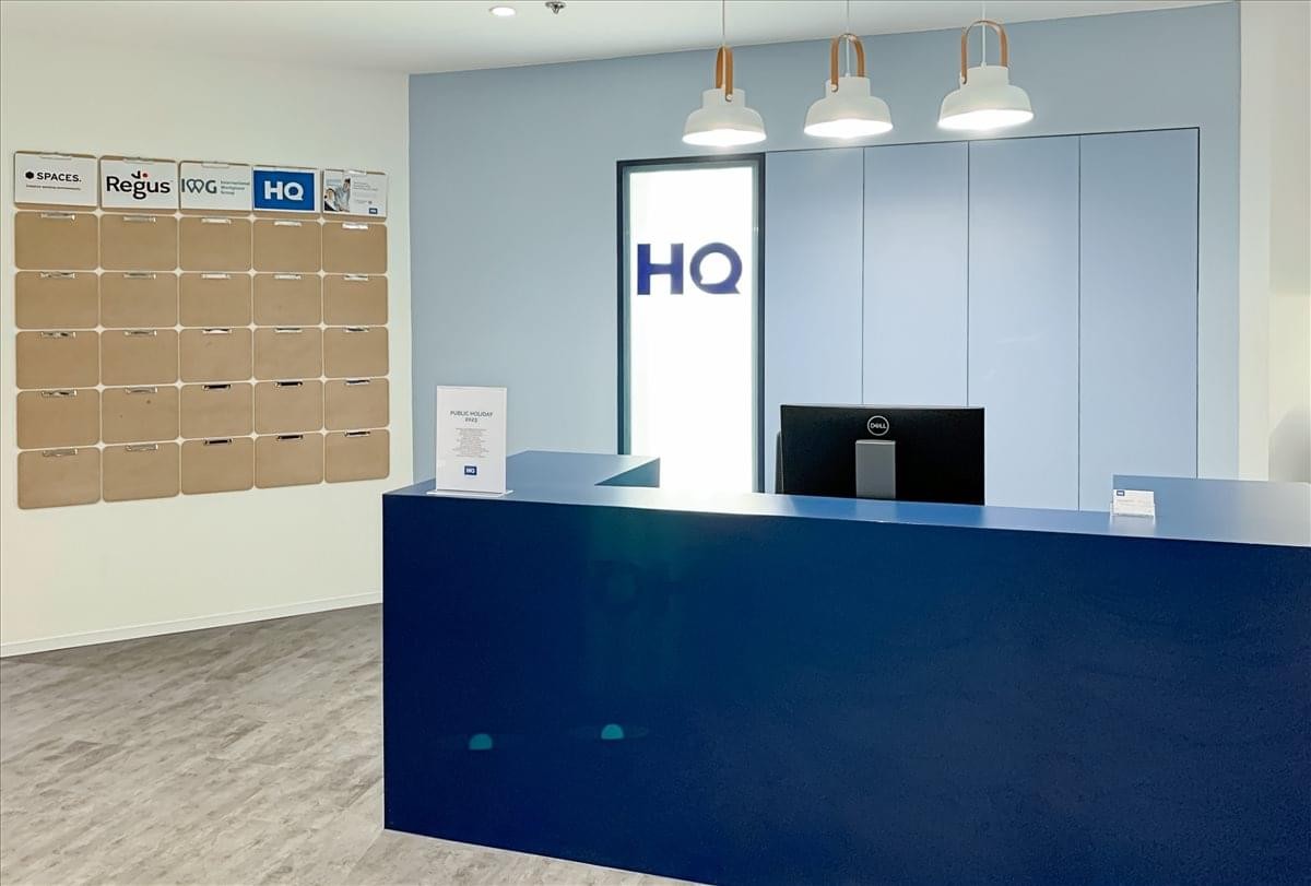 Deep blue professional reception desk with pendant lighting and branded signage.