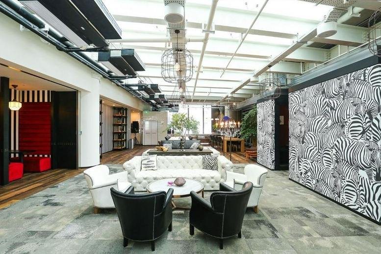 Spacious communal lounge at Tower 2 Yintai Centre with zebra-print wall and natural skylight.