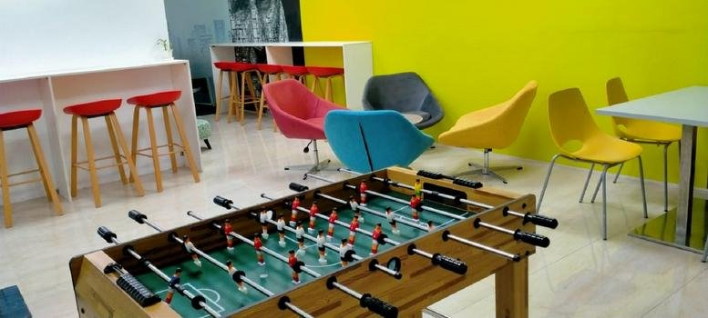 Vibrant communal breakout area with a foosball table and colorful modern seating at Noida One.
