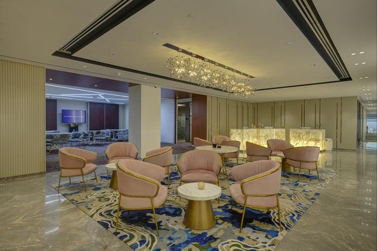 Spacious reception area at Level 10, Tower C, Panchshil Business Park Phase 2 with plush pink chairs and a blue rug.