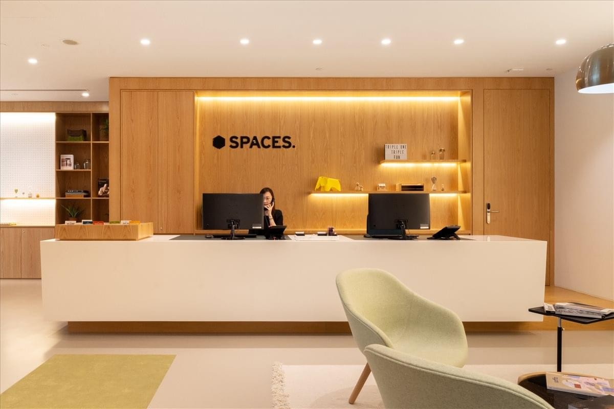 The sleek, modern reception area at TripleOne Somerset with a long white desk and wood-paneled walls.