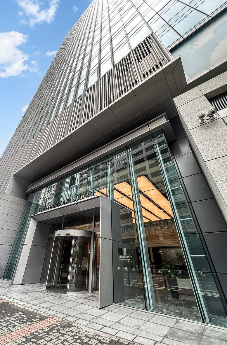 Exterior entrance of Two Harbour Square featuring a grand glass facade and revolving doors.