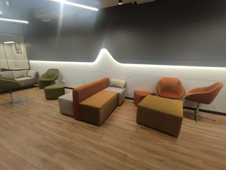 Bright communal lounge area with colorful modular seating and warm wood flooring.