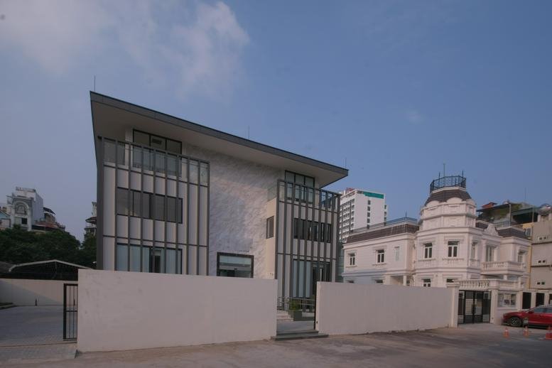 Wide view of a modern multi-story office building with stone cladding and dark vertical louvres.