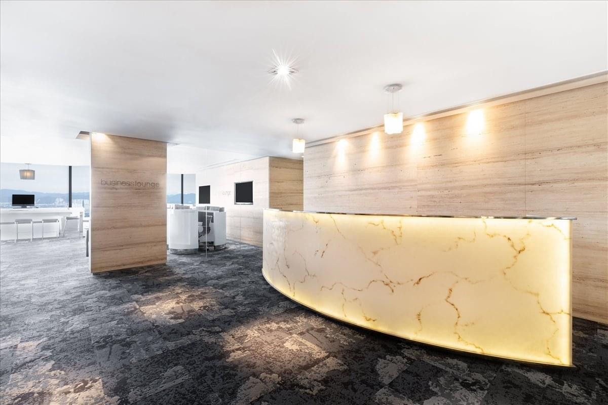 Spacious reception area with a curved, backlit marble desk and warm wood-paneled walls.