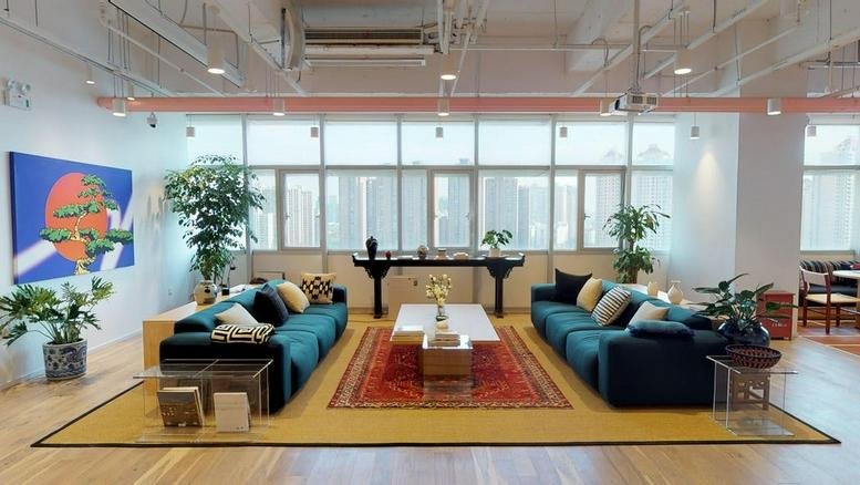 Spacious communal lounge at Waterfront Park with two large blue sofas, plants, and a colorful feature painting.