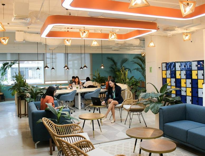 Spacious lounge at West Aeropark Industrial Estate with orange light fixtures, blue sofas, and wooden accents.