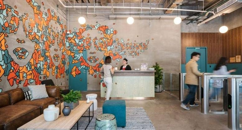 Reception lobby at WeWork The Center, 989 Changle Road with a vibrant mural and leather seating.