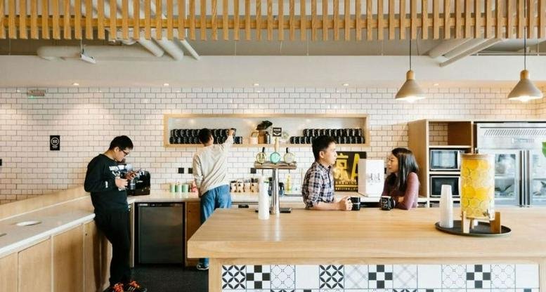Modern communal kitchen with high-top tables and people enjoying coffee