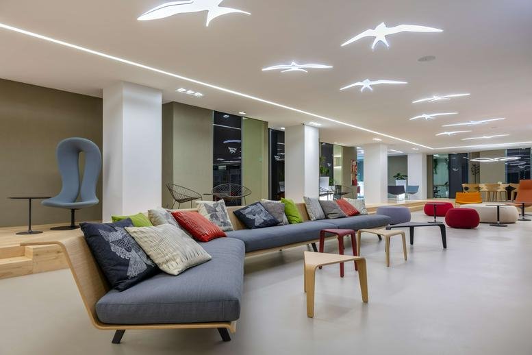 Spacious communal lounge at Wui Wah Factory Building with bird-shaped ceiling lights and grey sectional sofa.