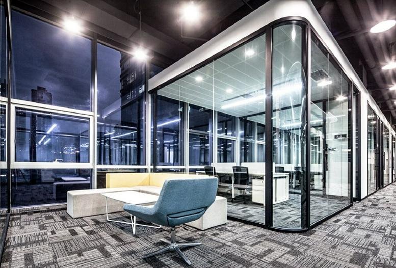 Lounge area with blue armchair and glass-walled private offices at Xinhao E Du, Podium Building.