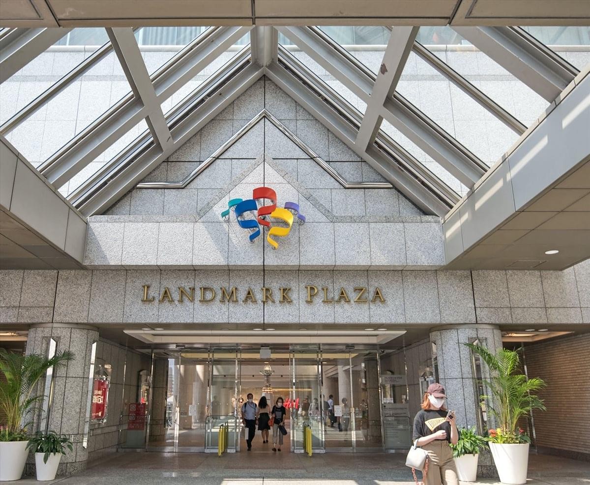 Entrance to the Yokohama Landmark Plaza featuring a glass atrium roof and palm trees.