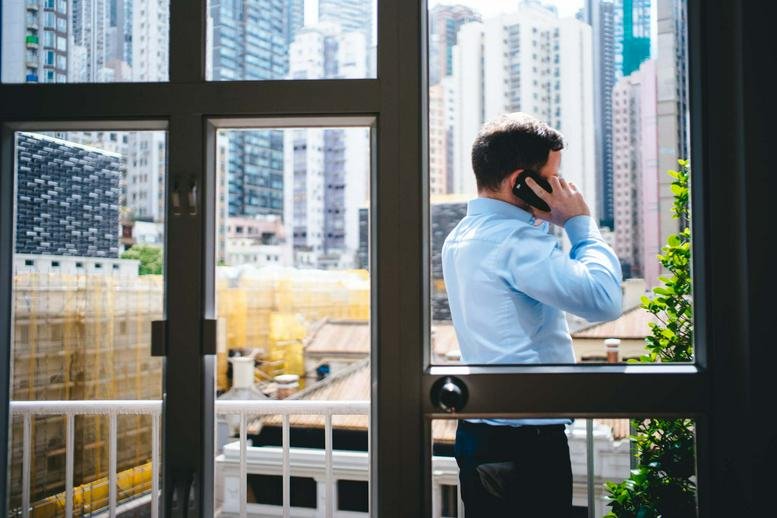 A man on a phone call overlooking the city skyline from the Yu Yuet Lai Building.