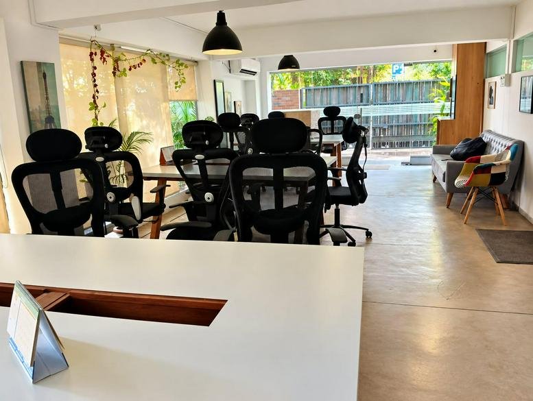 Spacious open-plan workspace with ergonomic black chairs and large windows providing natural light.