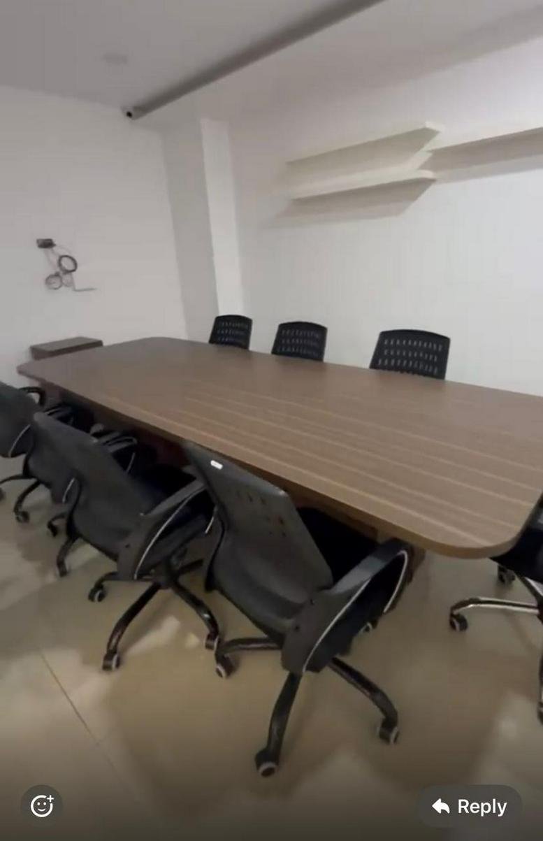 Meeting room at SOUTH-WING,, featuring a long wood-grain conference table and black mesh swivel chairs.