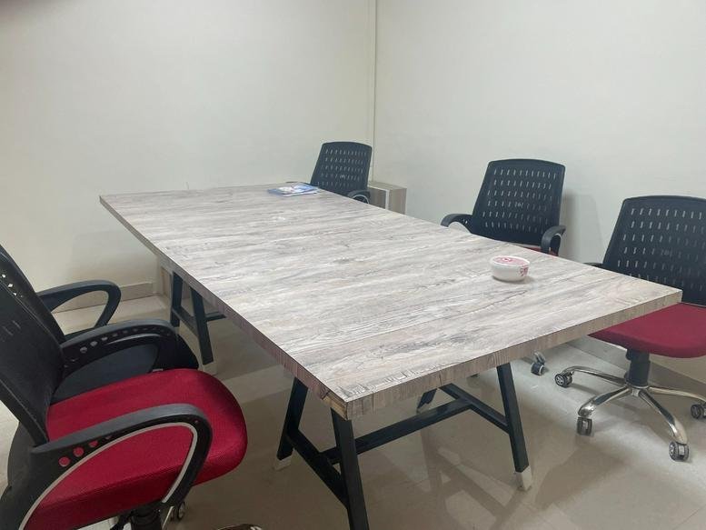 Meeting room at Spurlink, Phase 8 featuring a light wood table and red-accented chairs.