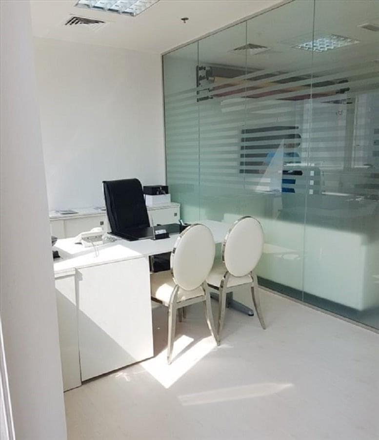 Private office with white desk, black leather chair, and glass partition at Barsha Heights, Tecom, Dubai.