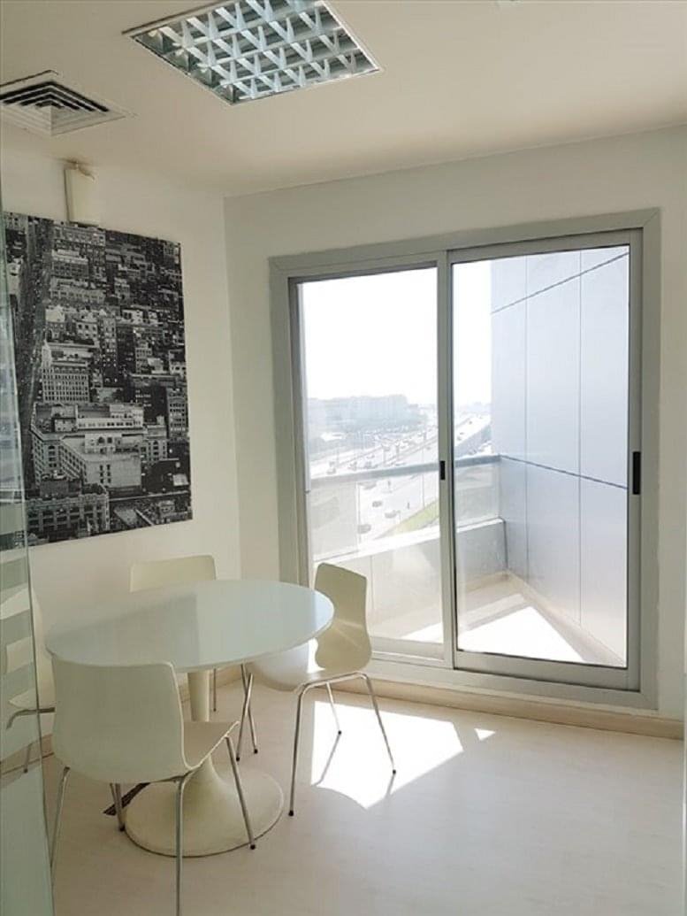Bright dining area at Barsha Heights, Tecom, Dubai with a white pedestal table next to a sliding glass balcony door.