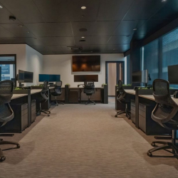 Open-plan office space featuring multiple workstations and ergonomic chairs.