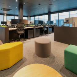 Collaborative breakout area with colorful ottomans and expansive windows.