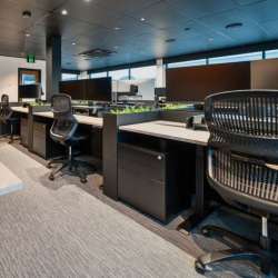 Modern office setup showing ergonomic chairs and desks with monitor screens.