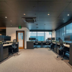 Wide view of a carpeted open-plan office with a dark, modern ceiling.