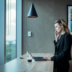 Professional woman working on a laptop at a high table with city views.