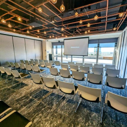 Large presentation room with rows of chairs and a projector screen.