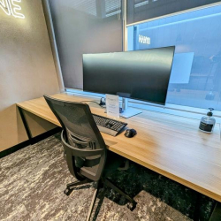 Individual workstation featuring an ultrawide monitor and wooden desk.