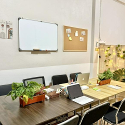 Shared workspace featuring a large wooden table, whiteboard, and corkboard on the wall.