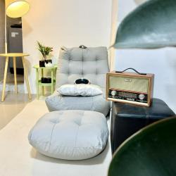 Relaxing corner with a padded floor seat, ottoman, and a vintage-style radio.