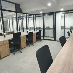 Spacious coworking area with wooden desks and black chairs.