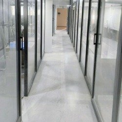 Bright hallway with glass-enclosed office rooms on both sides.