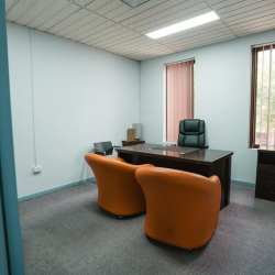 Minimalist private office with orange armchairs and grey carpeting.