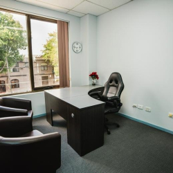 Well-lit small office suite with a corner desk and natural light from a large window.