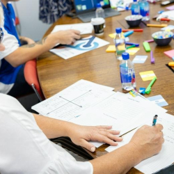 Creative workshop table scattered with colorful sticky notes, markers, and planning documents.