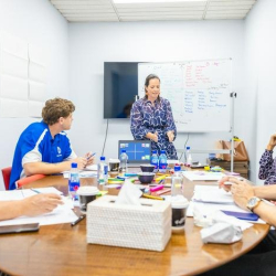 Collaborative training room with attendees seated around a large table during a presentation.