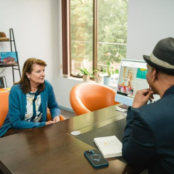 Client meeting area showing a desktop monitor and a view of trees through a large window.
