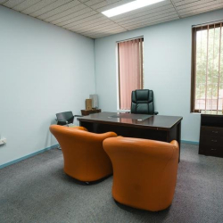 Private two-person office suite featuring vibrant orange tub chairs and a large window.