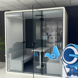 Glass-enclosed private meeting booth with white sofa and small table.