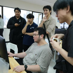 Team members gathered around a computer screen in a collaborative workspace.