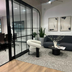 Inviting lounge area with a dark sofa, white bouclé armchair, and vibrant greenery.