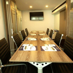 Professional boardroom featuring a long wood-grain table and sleek black chairs