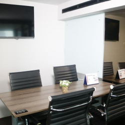 Compact meeting room with a wooden table and wall-mounted presentation screen