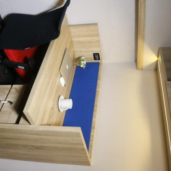 Close-up of a single office desk with a blue privacy panel and wooden finish