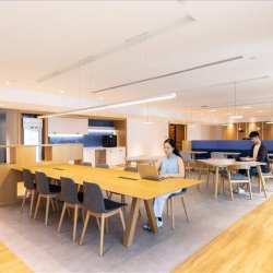 Modern open plan coworking space with long wooden tables, Central Plaza, Wan Chai, Hong Kong.