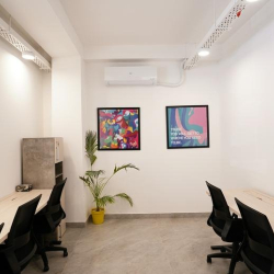 Modern interior workspace featuring white desks, ergonomic black chairs, and vibrant abstract wall art.