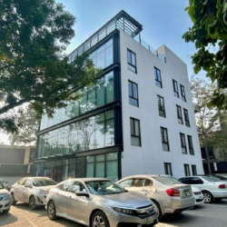 Modern multi-story office building with a white facade and large windows under a clear sky.